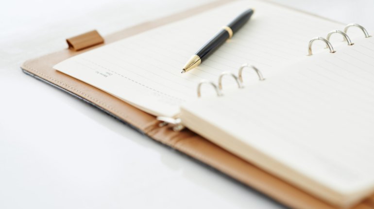 Close-up of open personal organizer with pen